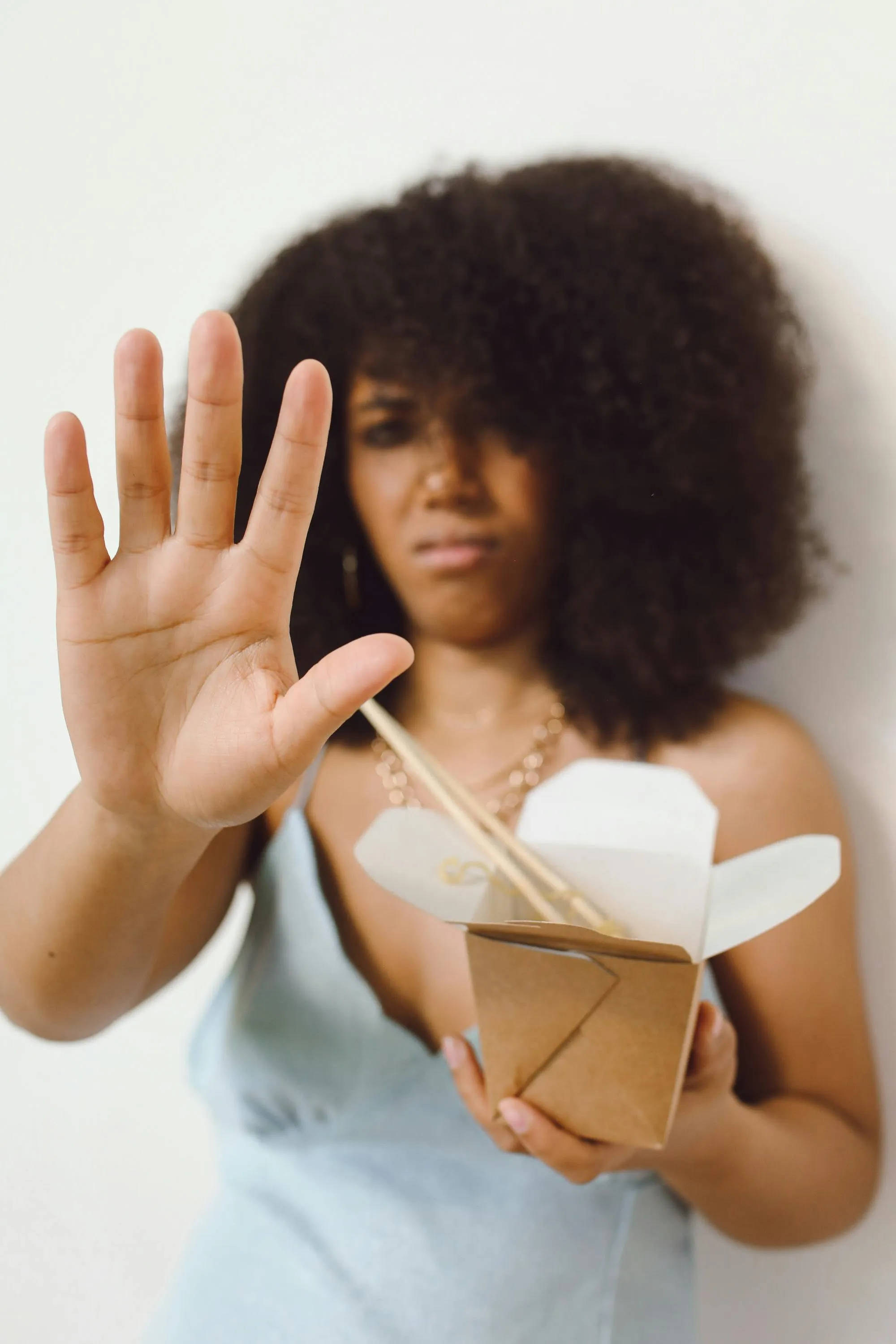 A woman holds out her hand to redirect a greeting while at a table