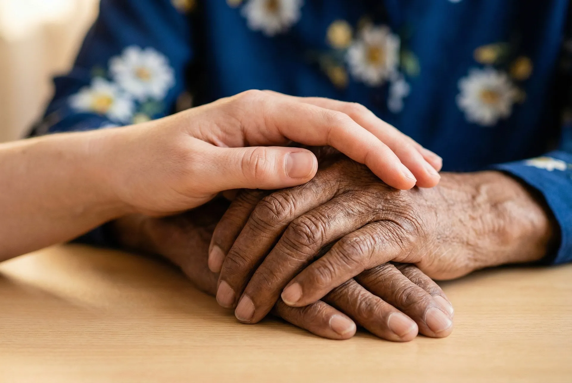 Two sets of hands touching on a desk in a professional setting