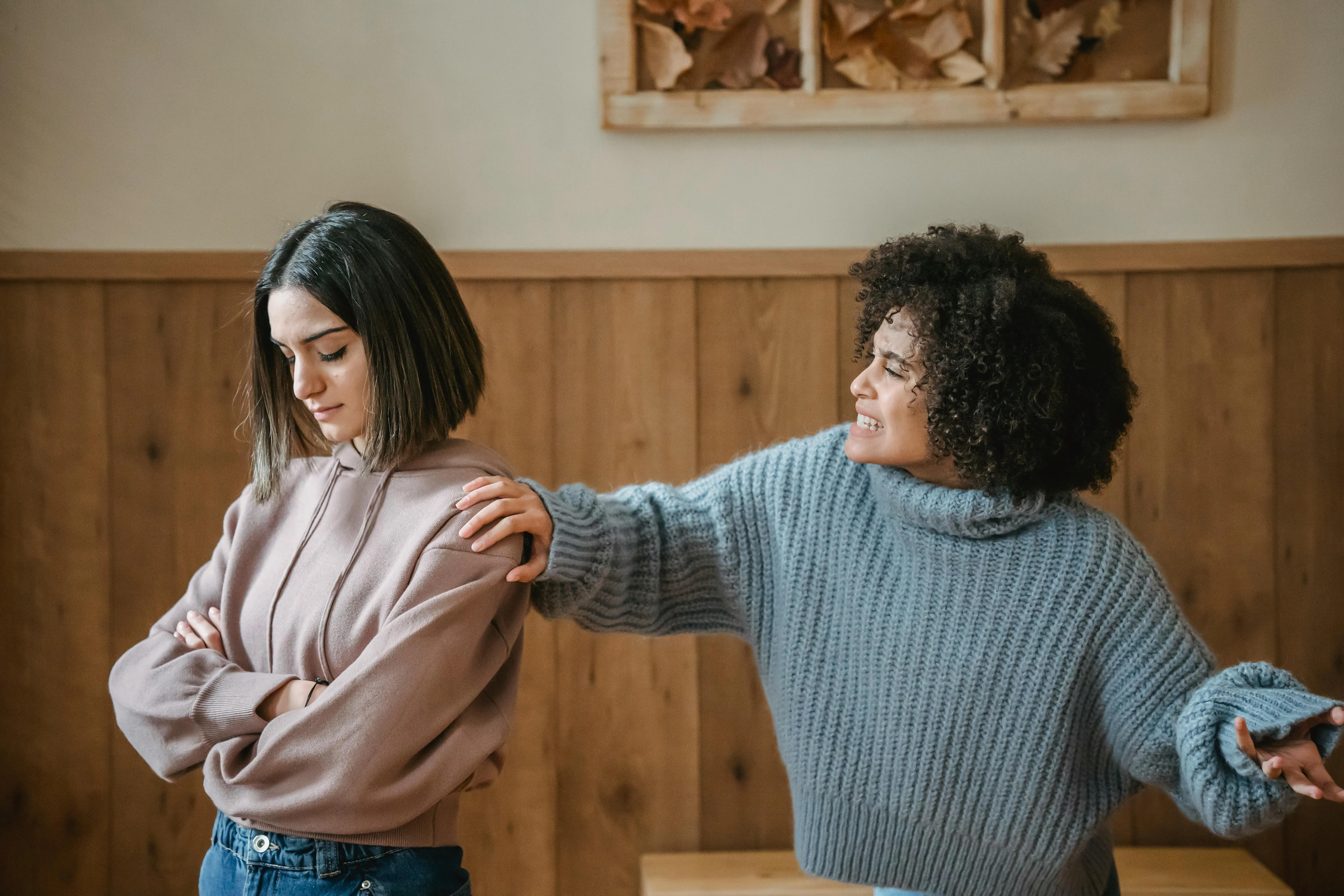 One coworker grabs the other's shoulder during a conversation