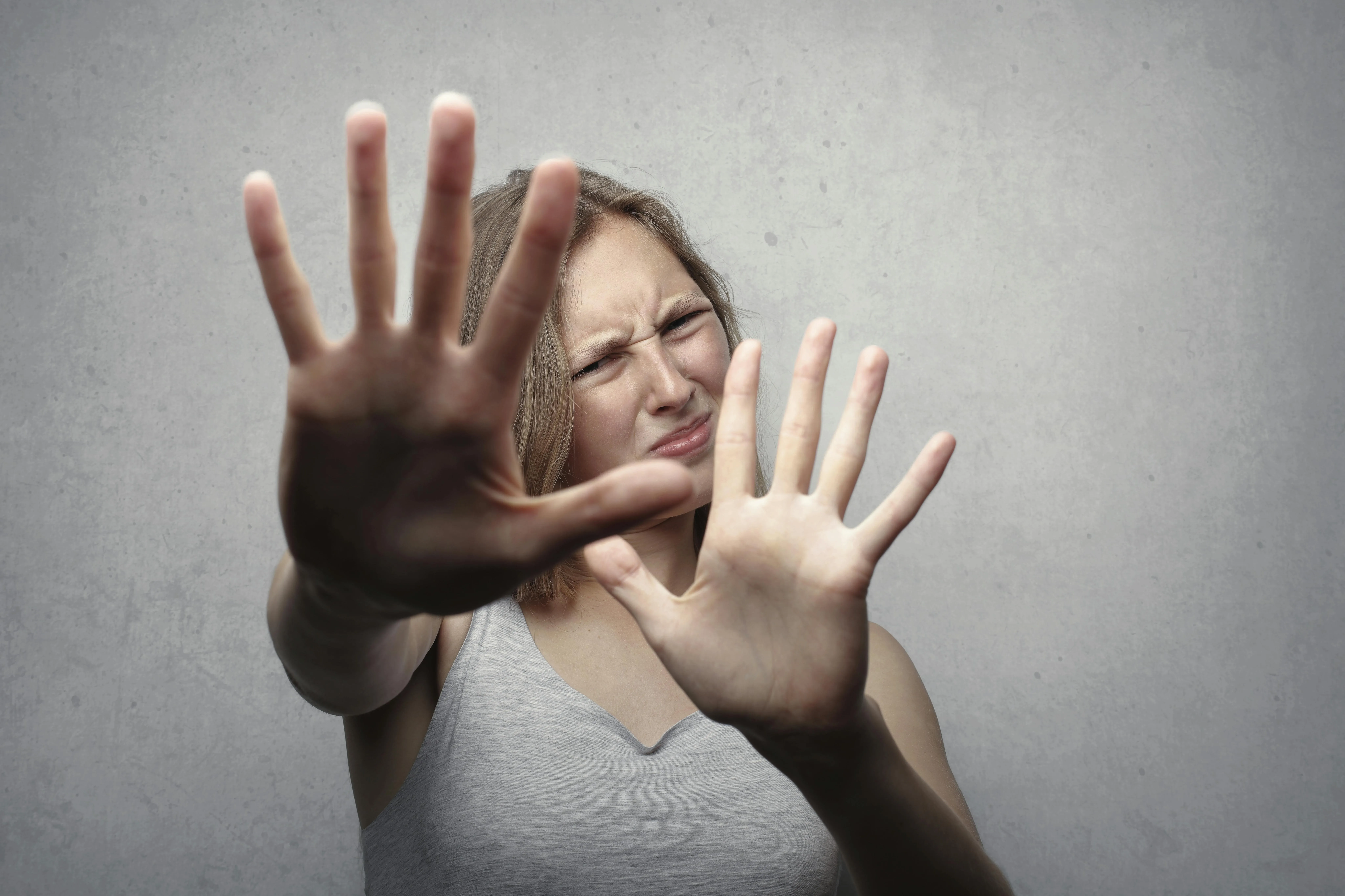 A woman holds up both hands to ward off unwanted contact